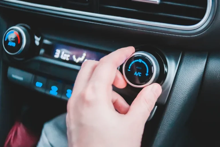Hand am Drehregler der Klimaanlage im Auto