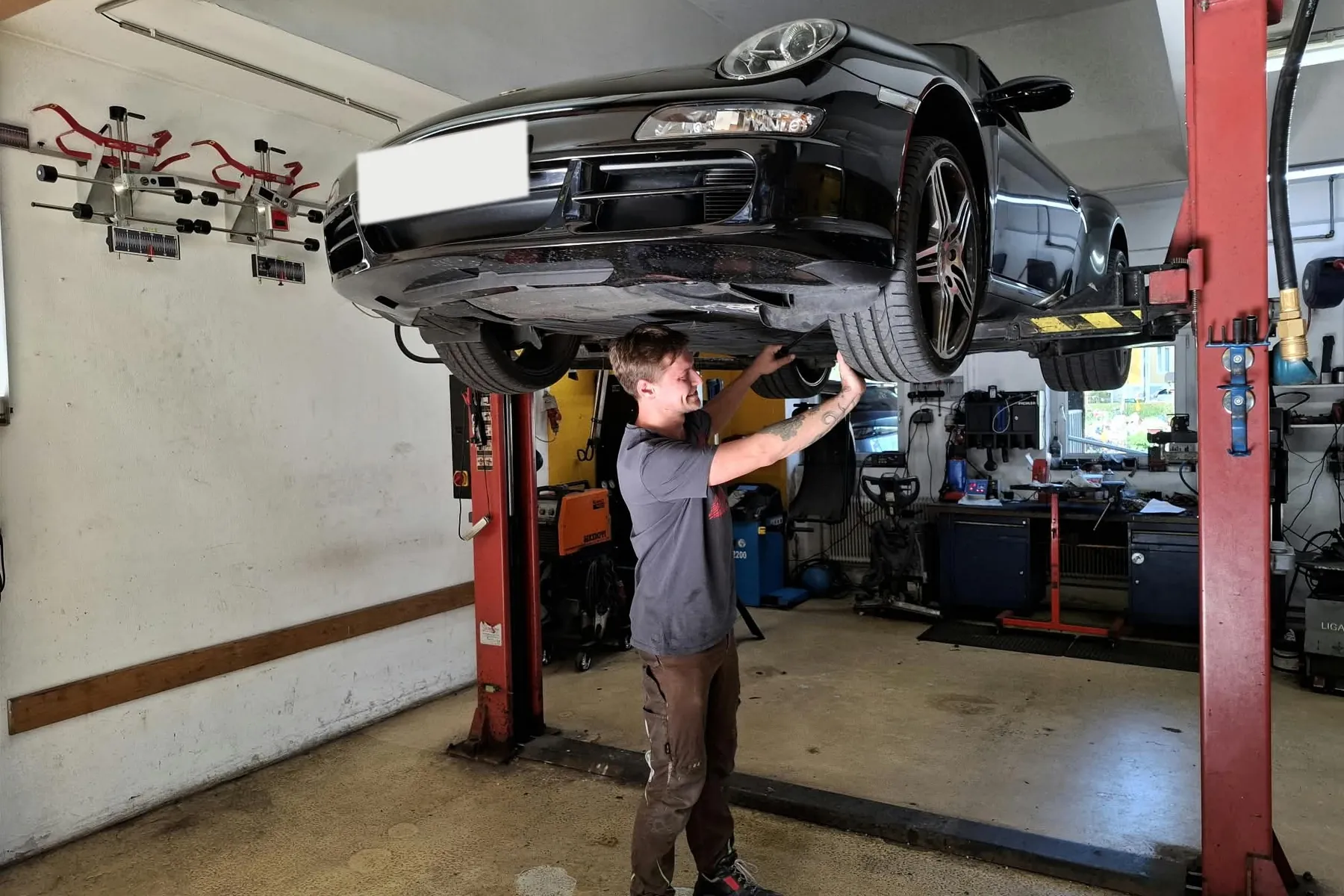 Auto auf der Hebebühne in der Werkstatt in Ligist, darunter ein Mitarbeiter