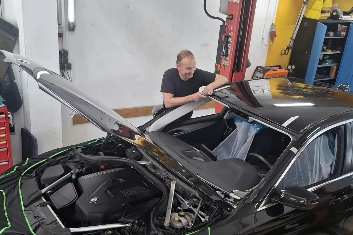 Mitarbeiter über dem geöffneten Motorraum in der Werkstatt in Ligist